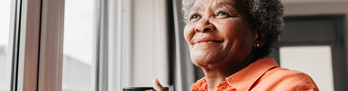 A smiling older woman holding a mug