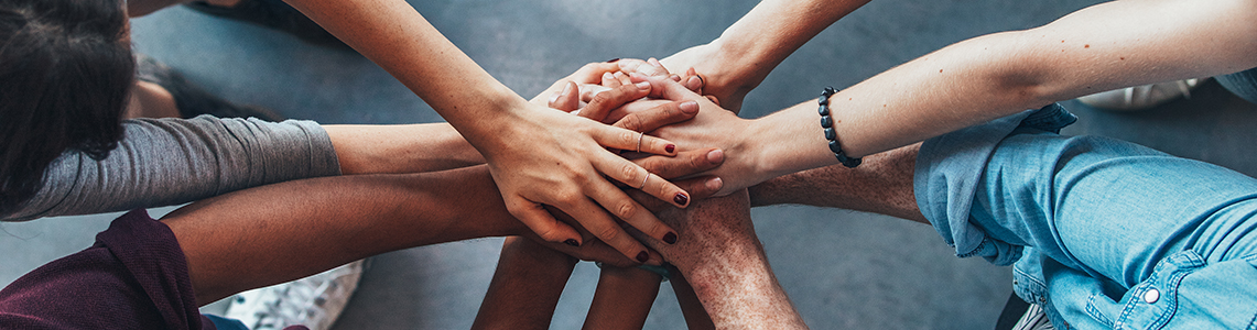 A huddle of people putting their hands together in a circle